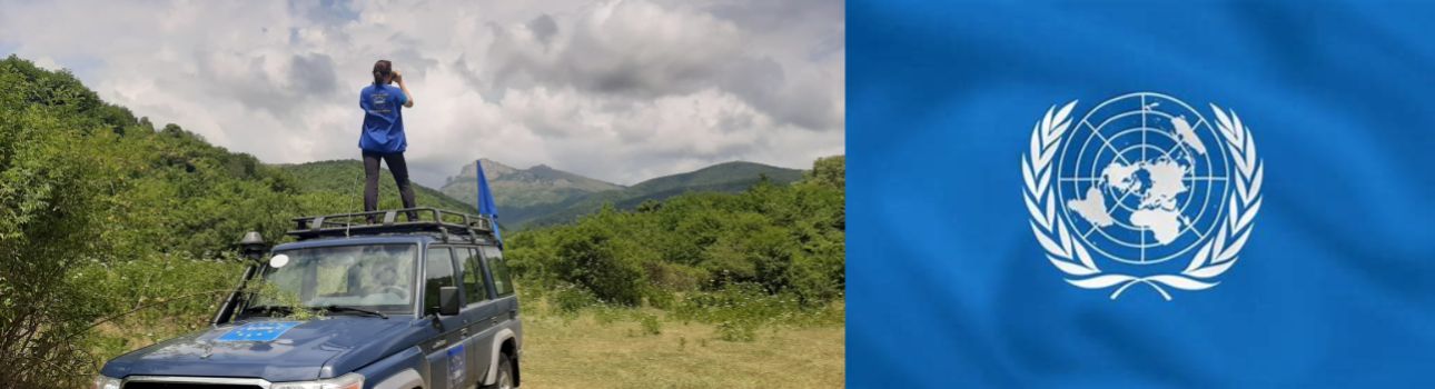 Funkcjonariuszka na samochodzie obserwuje przez lornetkę, z prawej strony flaga ONZ.