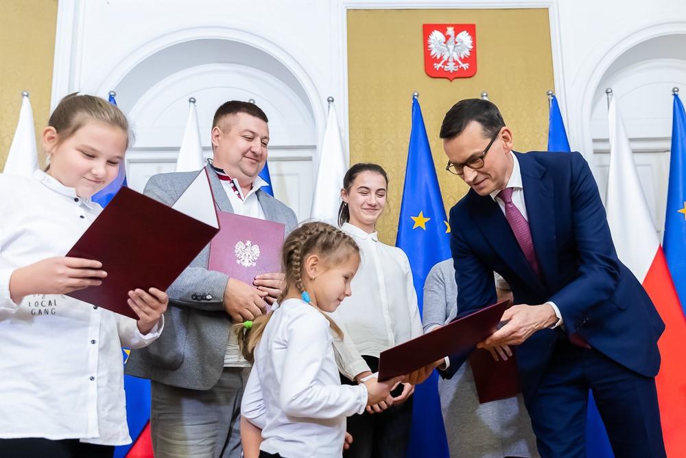 Premier Mateusz Morawiecki wraz z rodziną repatriantów.