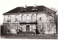 zdjęcie archiwalne, czarno-białe - zabytkowy, zdewastowany dworek w otoczeniu parku