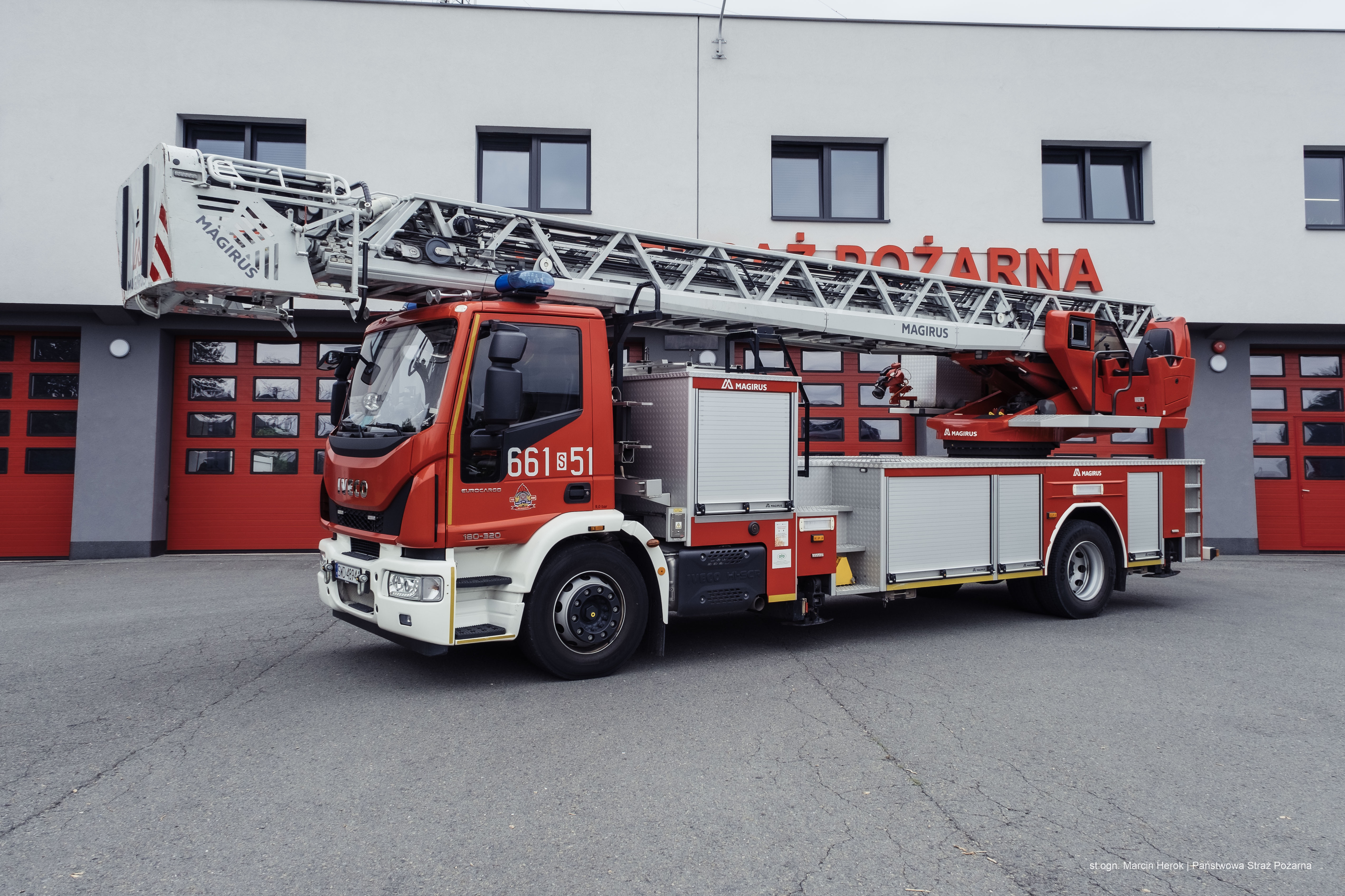 Zdjęcie przedstawia drabina mechaniczna o wysięgu do 42m SCD 42. W tle budynek Państwowej Straży Pożarnej.