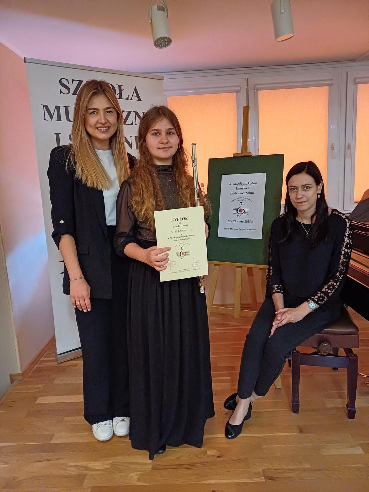 Na zdjęciu widoczna jest uczennica wraz z nauczycielką fletu oraz akompaniatorką. 