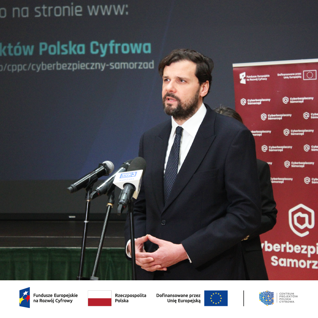 Przemawiający Wojciech Szajnar Dyrektor CPPC na tle ścianki Cyberbezpieczny Samorząd 