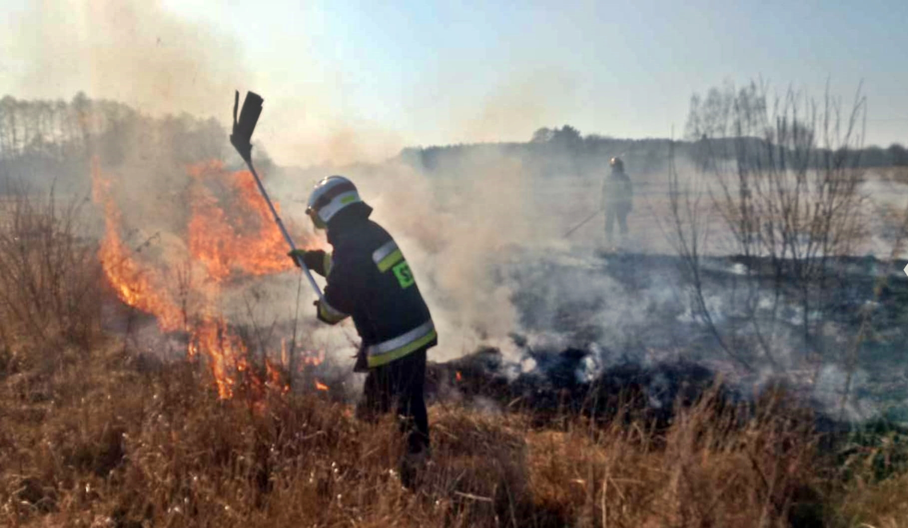 Na zdjęciu strażak gaszący tłumicą płomień pożaru traw.