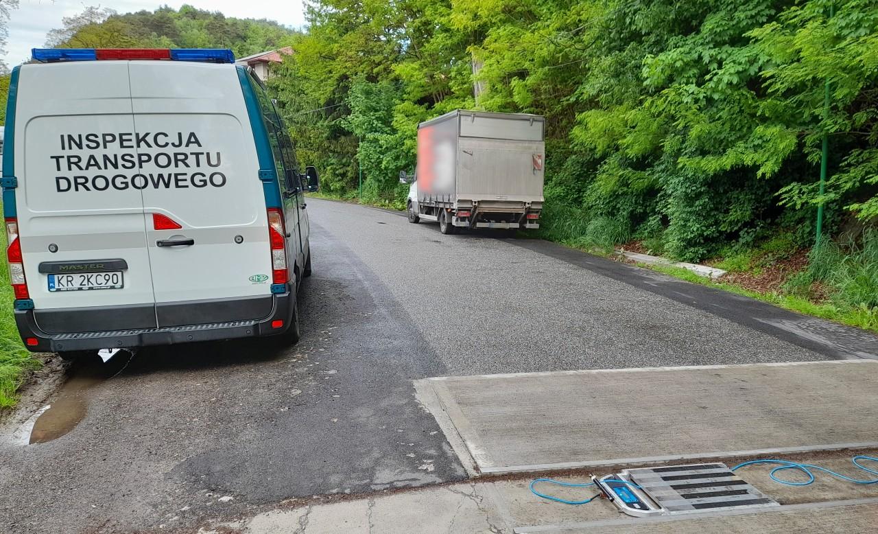 Radiowóz, wagi ITD i stojący za nimi przeładowany samochód dostawczy.