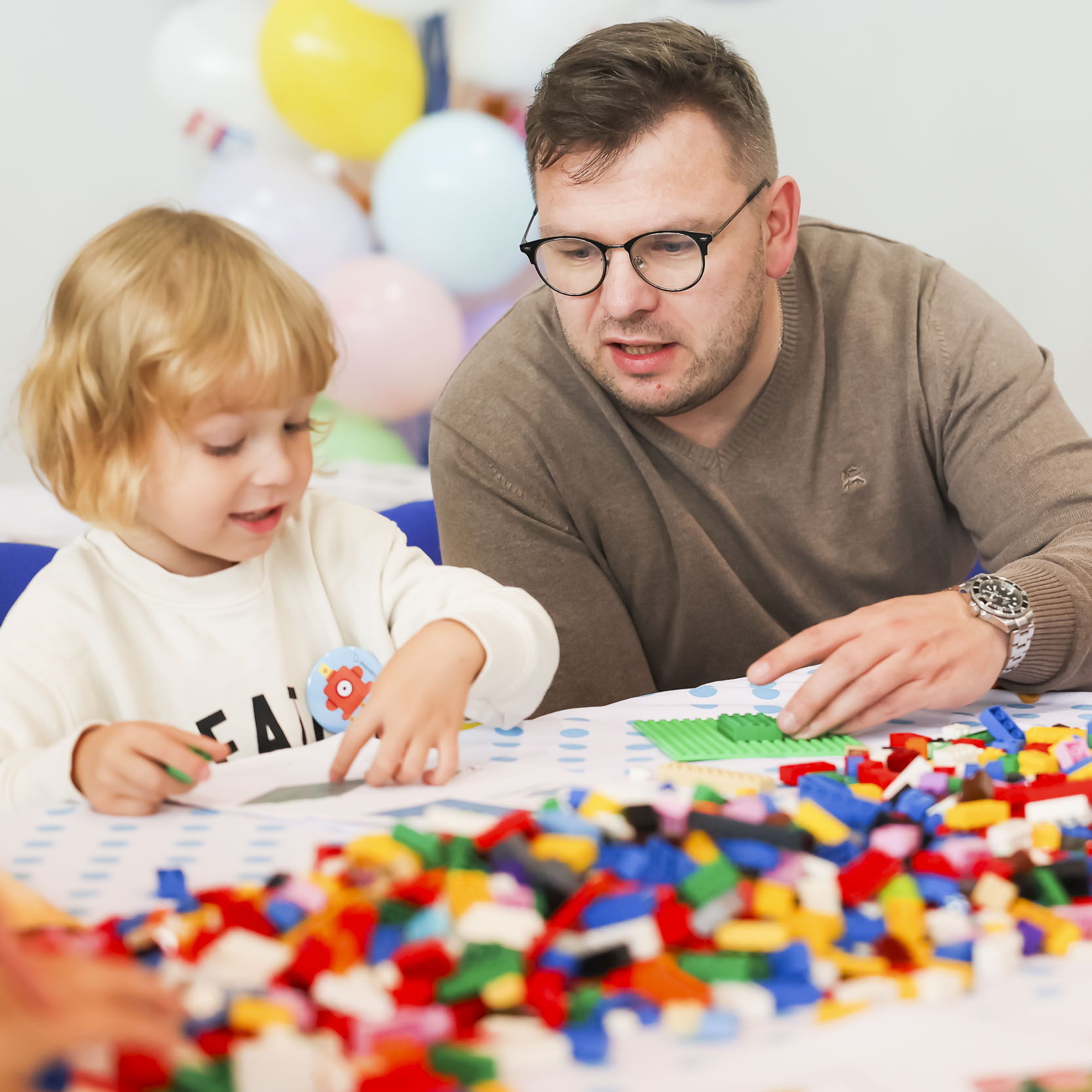 Dziecko i rodzic układający klocki lego w trakcie warsztatów
