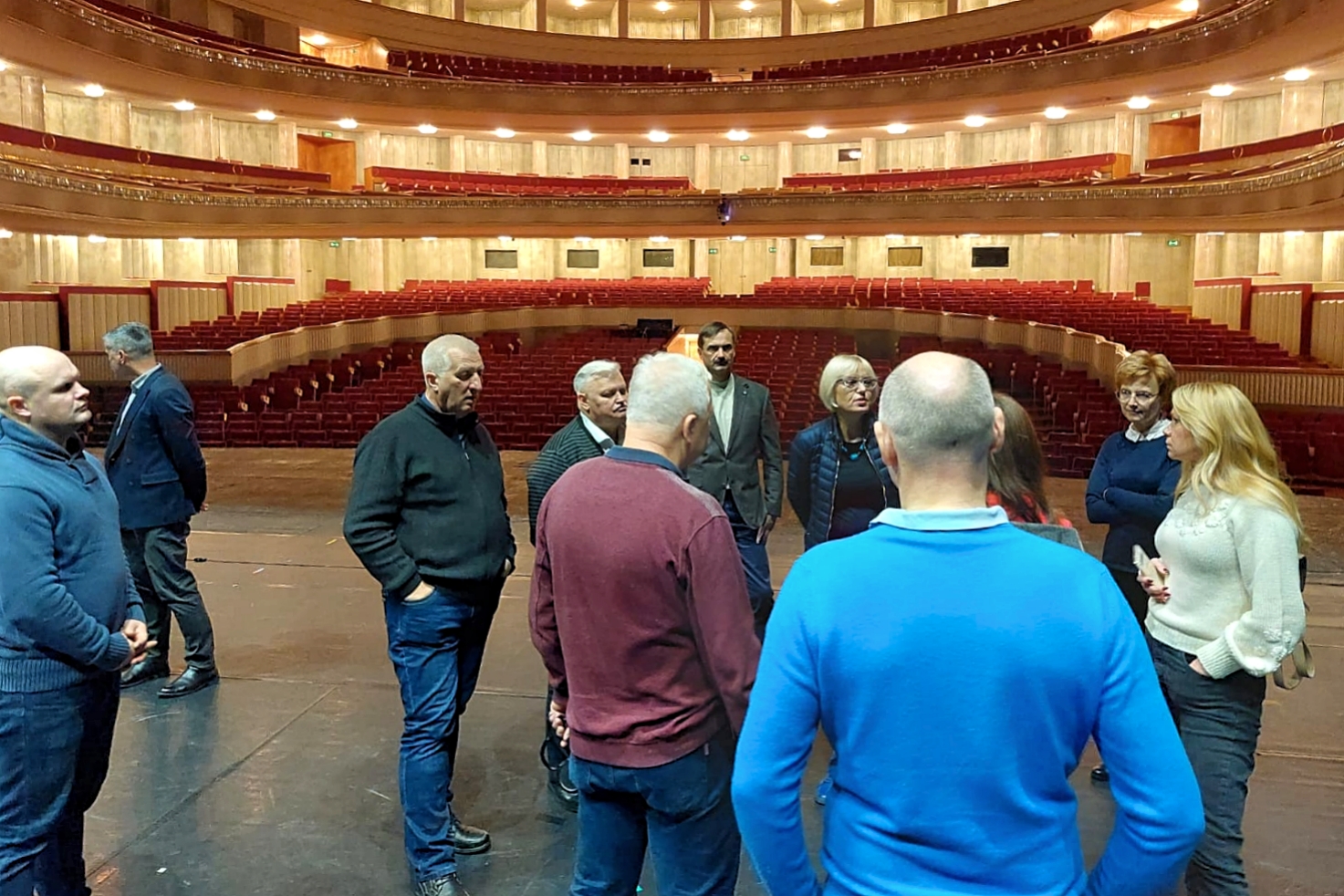 Litewska delegacja podczas wizytowania Opery Narodowej. Grupa osób stojąca na scenie opery w trakcie omawiania warunków ochrony przeciwpożarowej, zastosowanych rozwiązań technicznych i organizacyjnych. 