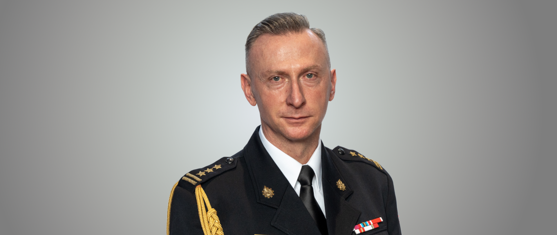 Zdjęcie portretowe przedstawia śląskiego komendanta wojewódzkiego PSP st. bryg. Damiana Legierskiego w mundurze wyjściowym z dystyngcjami i ze sznurem galowym