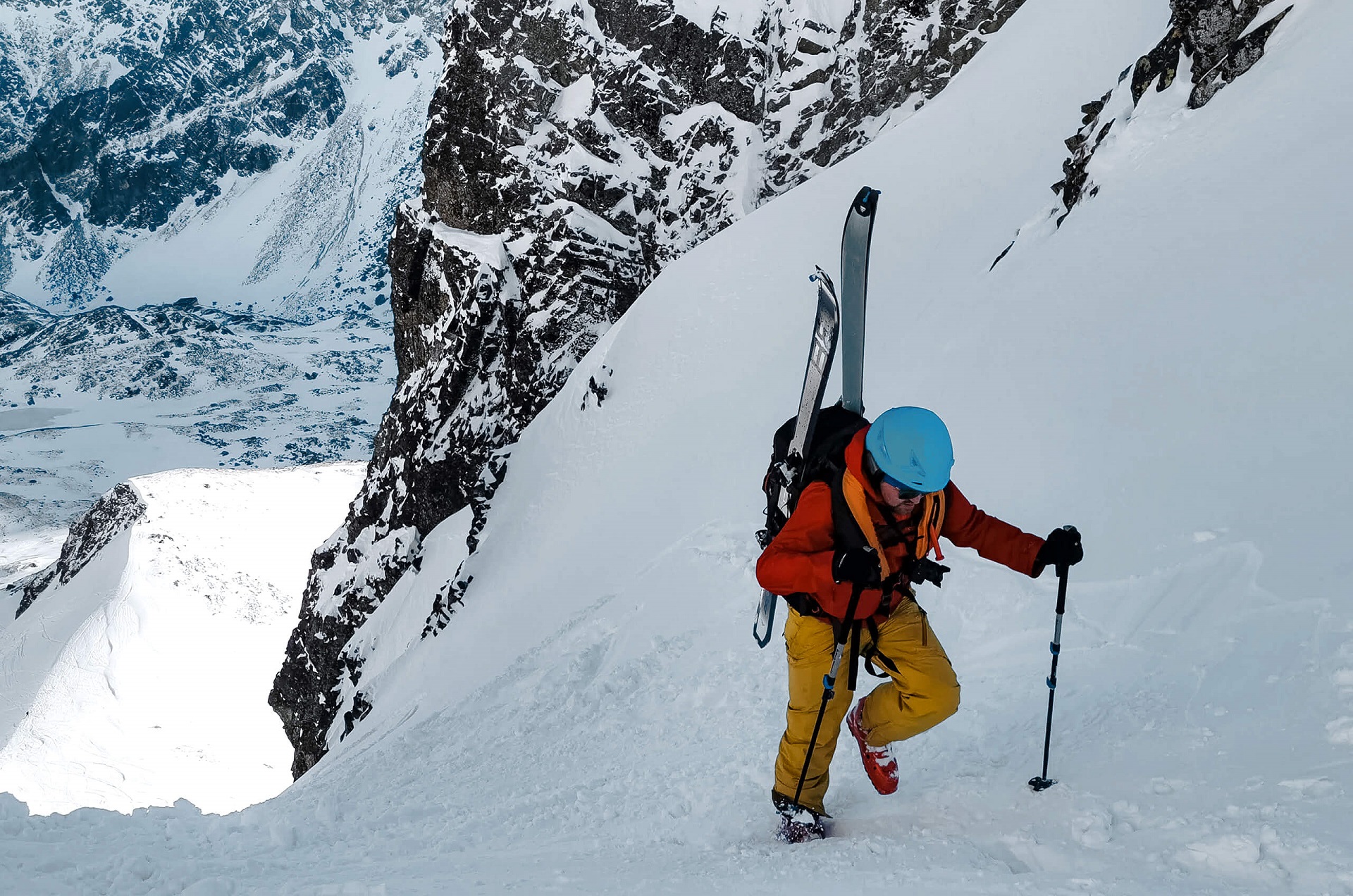 Mężczyzna z nartami podczas wspinaczki w górach, w zimie, z kamizelką lawinową AEROSIZE