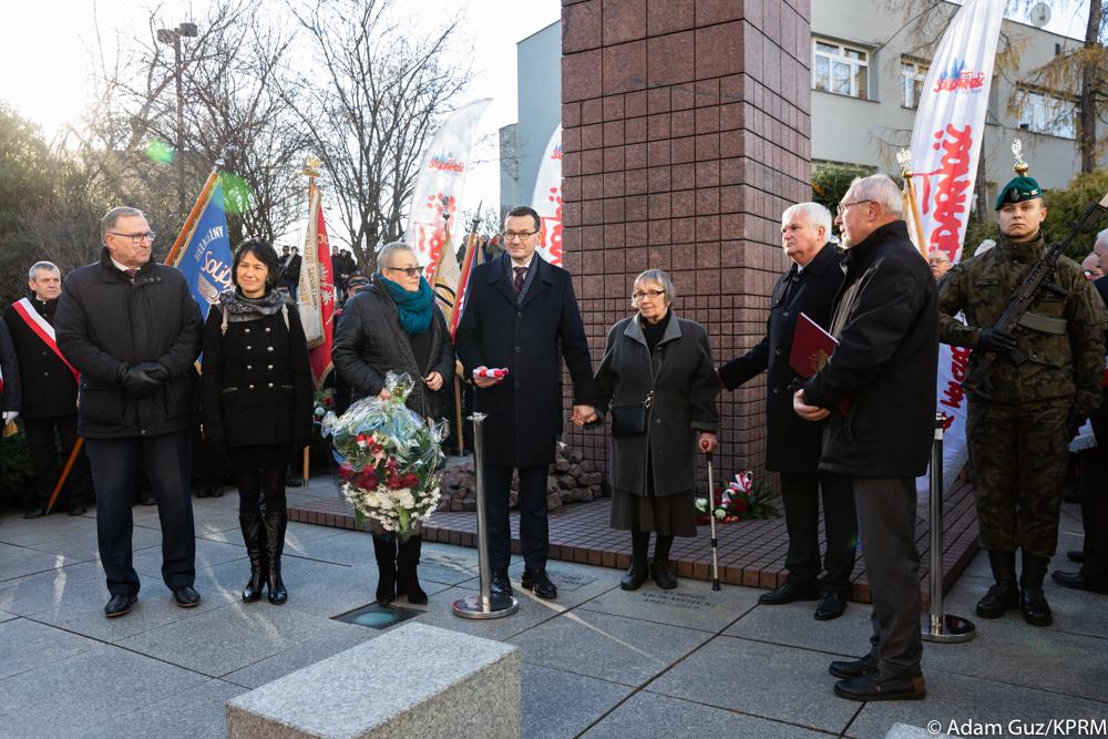 Premier Mateusz Morawiecki z rodziną przy tablicy upamiętniającej Kornela Morawieckiego.