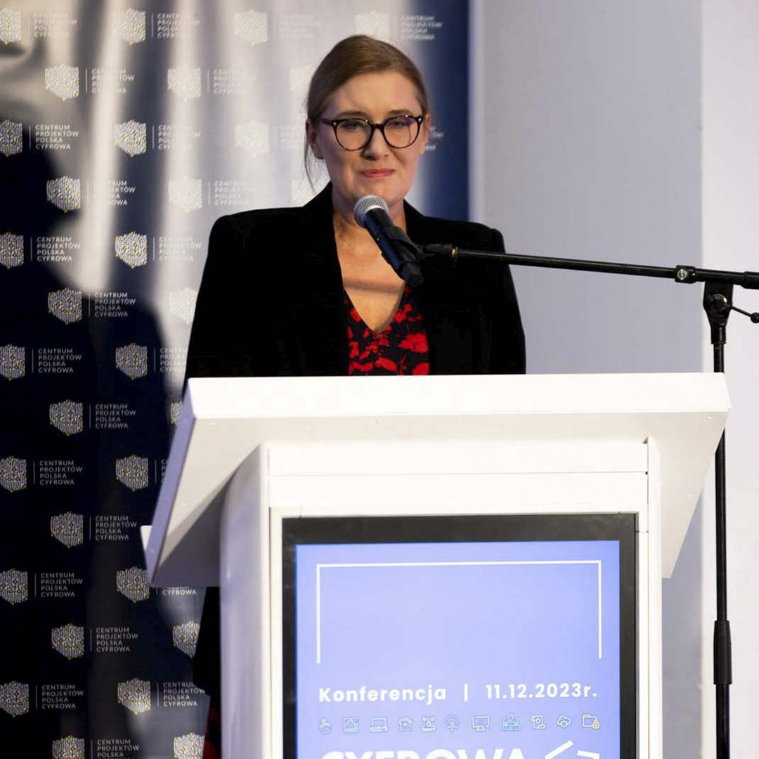 Dyr. Agnieszka Krauzowicz stoi przed mikrofonem i wita uczestników konferencji.