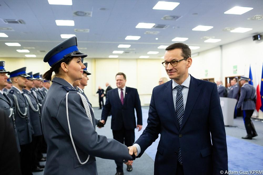 Premier Mateusz Morawiecki podaje rękę funkcjonariuszce policji.