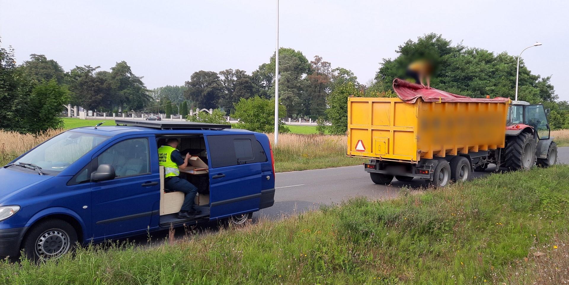 Po lewej stronie stoi nieoznakowany radiowóz wielkopolskiej ITD, a obok niego zatrzymany ciągnik rolniczy z przyczepą.