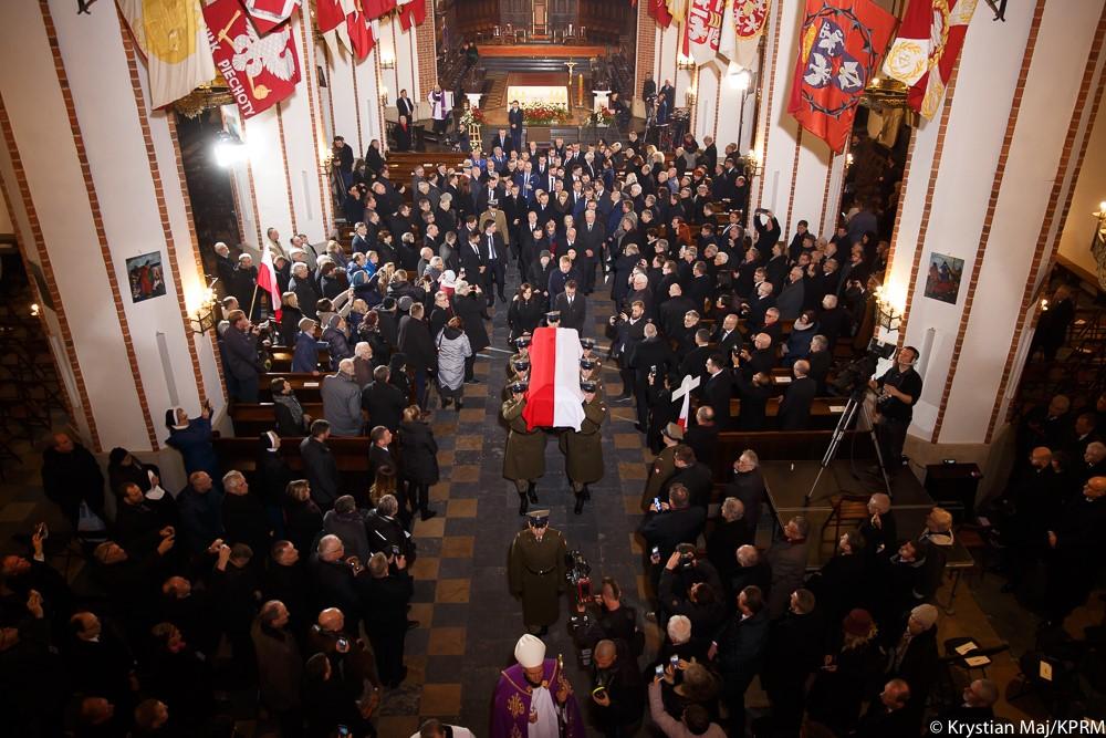 Widok z góry na uczestników uroczystości i trumnę wynosząną z archikatedry przez żołnierzy.