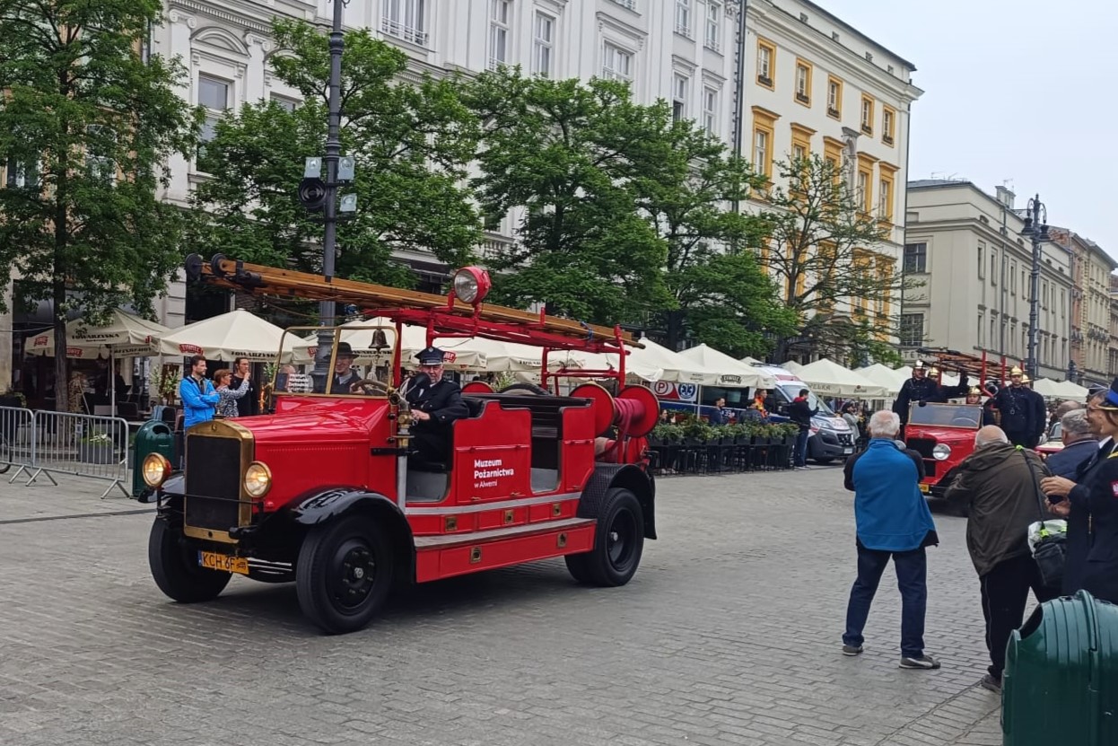 Ulicą Krakowa przejeżdżają dwa zabytkowe pojazdy straży pożarnej
