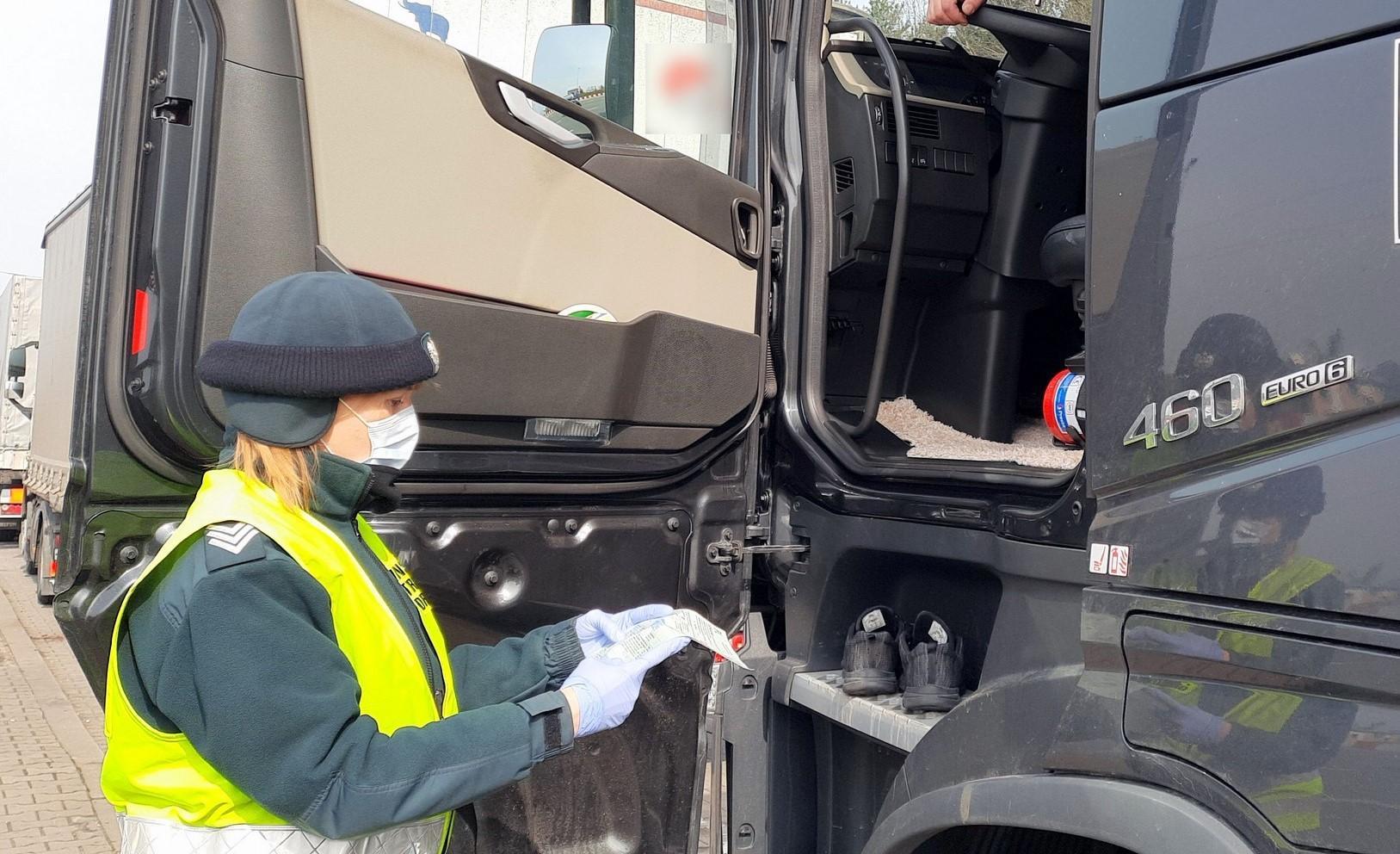 Inspektor pobiera dokumenty od kierowcy ciężarówki.