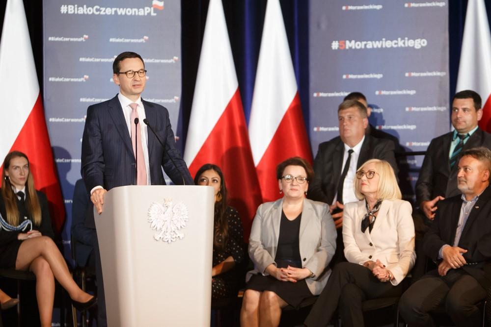 Premier Mateusz Morawiecki przy mówinicy, za nim siedzą minister Anna Zalewska i minister Joanna Kopcińska.