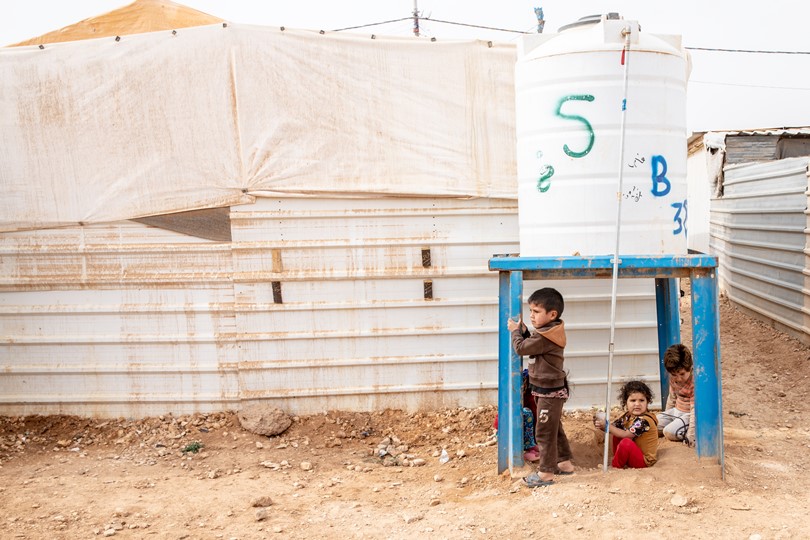 Dzieci bawiące się pod zbiornikiem w obozie w Jordanii