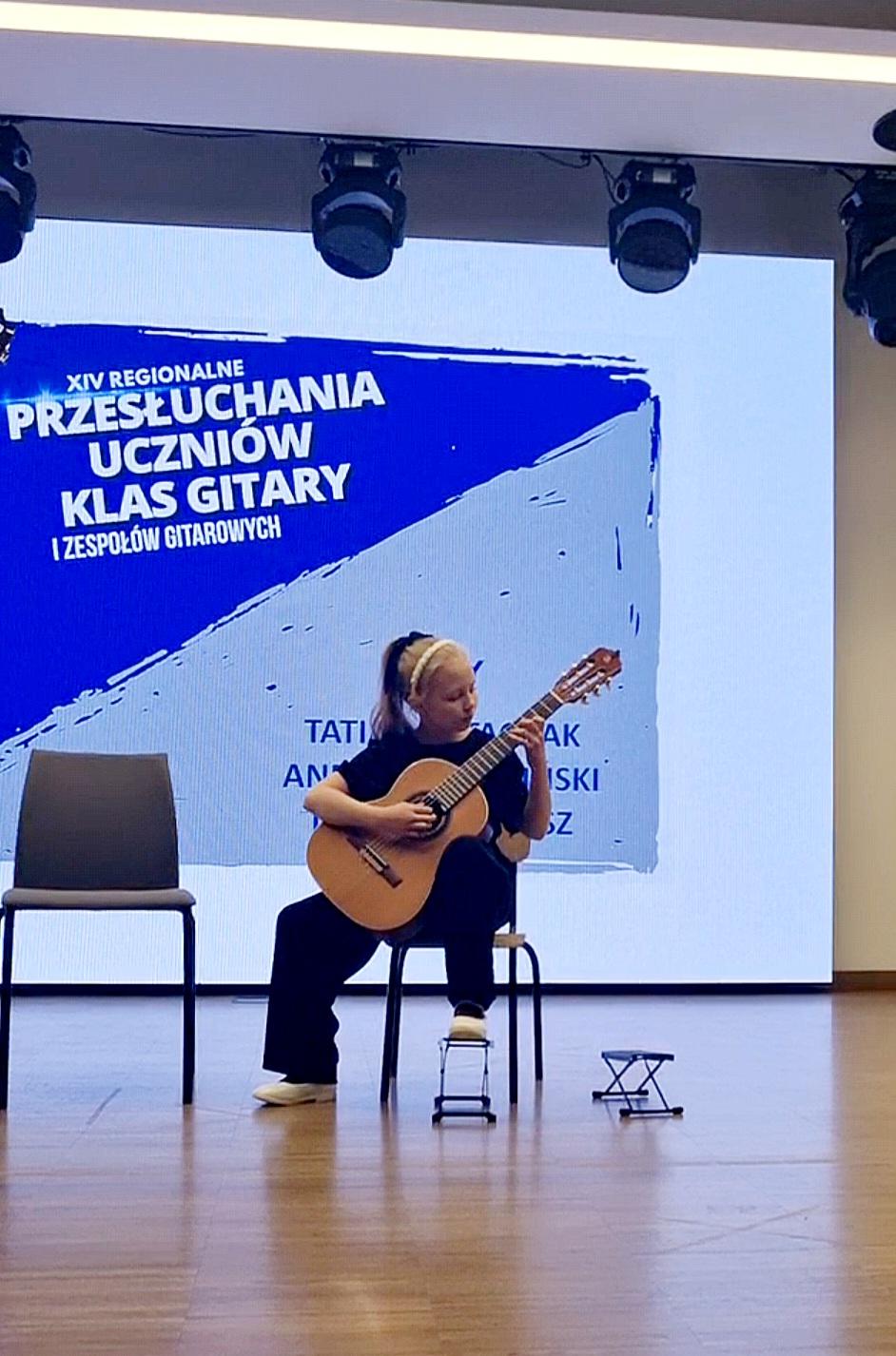 Zdjęcie uczennicy grającej na gitarze podczas prezentacji konkursowej