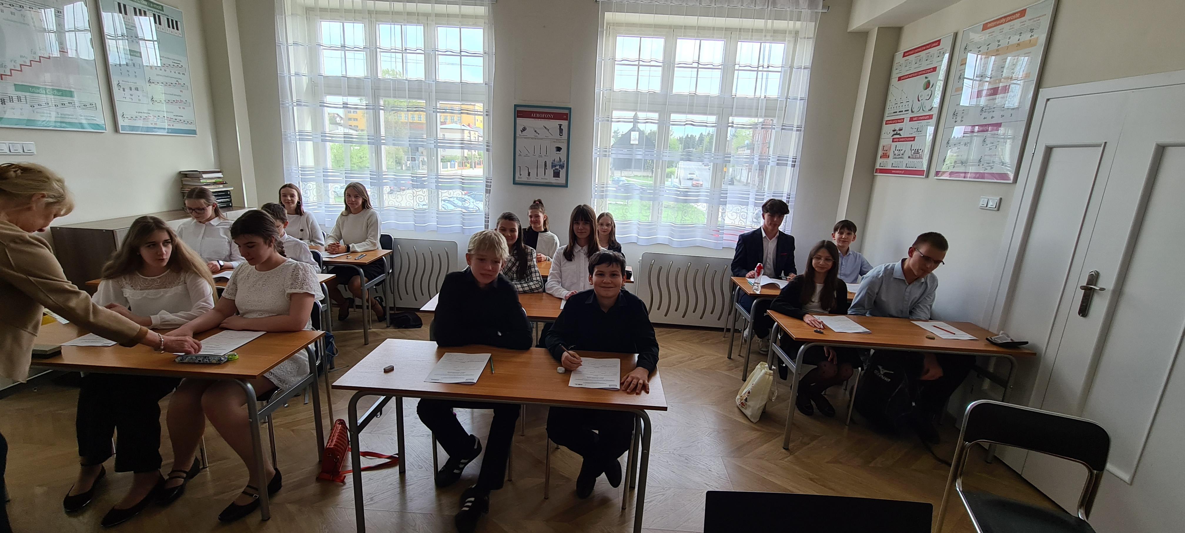 Zdjęcie uczniów w galowych strojach, którzy szykują się do pisania testu z kształcenia słuchu i audycji muzycznych