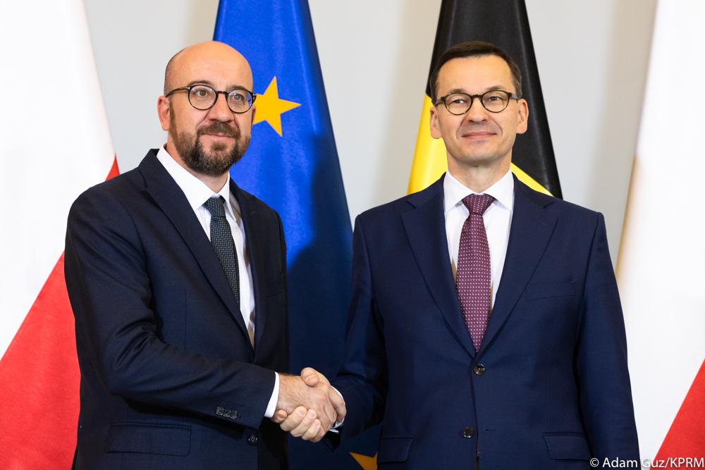 Premier Mateusz Morawiecki i premier Charles Michel na tle flag Polski, Belgii i Unii Europejskiej.