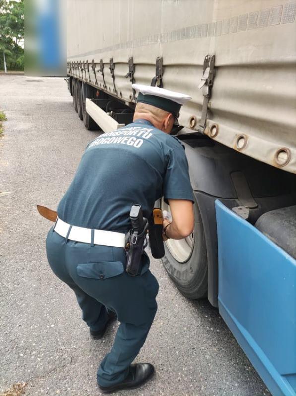 Inspektor obok koła ciągnika siodłowego