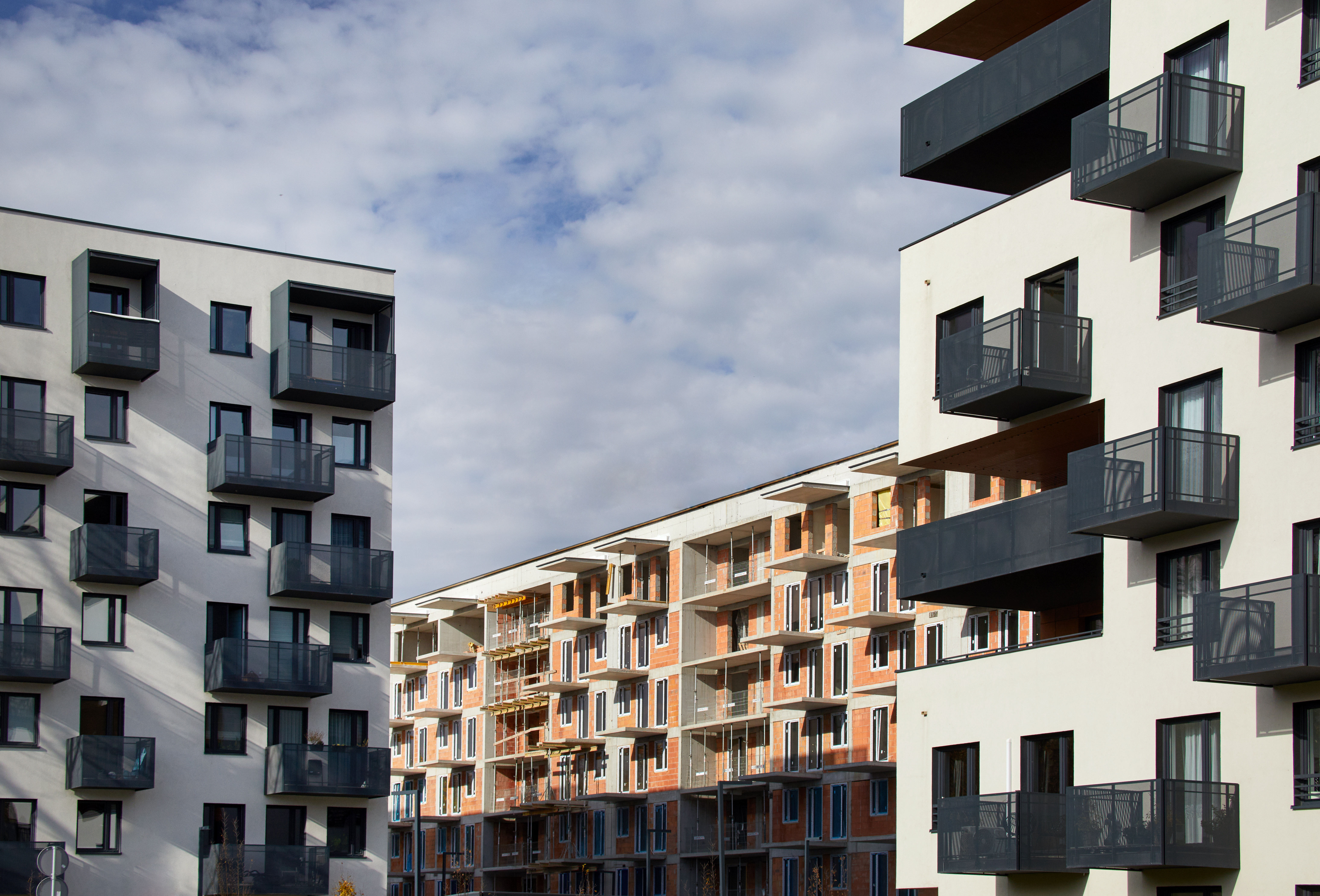 Po bokach dwa wykończone bloki mieszkalne, w środku jeden w trakcie budowy