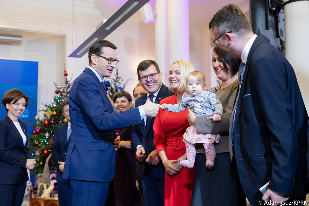 Premier Mateusz Morawiecki podaje rękę dziecku.