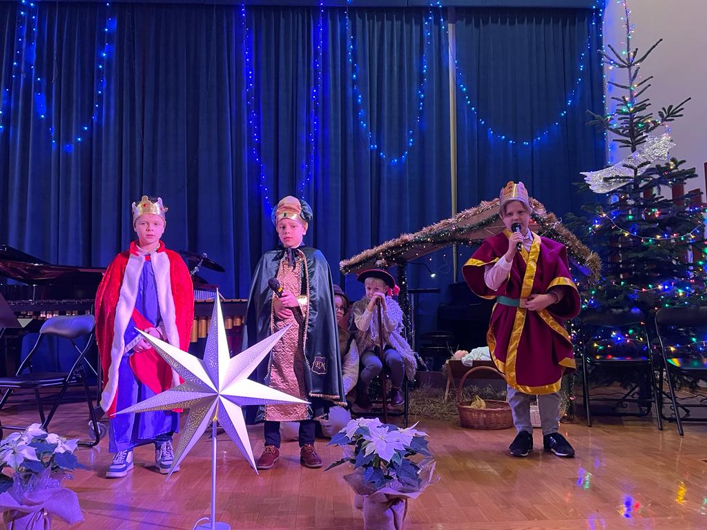 zdjęcie grupy przebranych w stroje Trzech Króli dzieci na tle dekoracji świątecznej