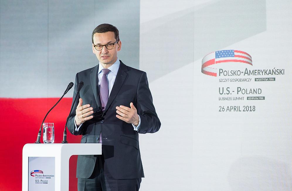 Premier Mateusz Morawiecki przy mówinicy, a w tle wyświetlona flaga Polski i nazwa szczytu.