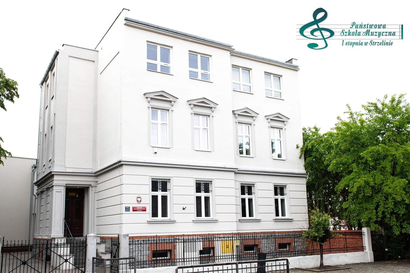Na zdjęciu znajduje się budynek PSM Strzelin po termomodernizacji widziany od strony ulicy Jana Pawła II. W górnej części znajduje się logo PSM Strzelin.