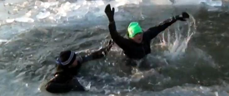 Zdjęcie przedstawia osobę w wodzie, pod którą załamał się lód i drugą postać która próbuje jej pomóc podając rękę.