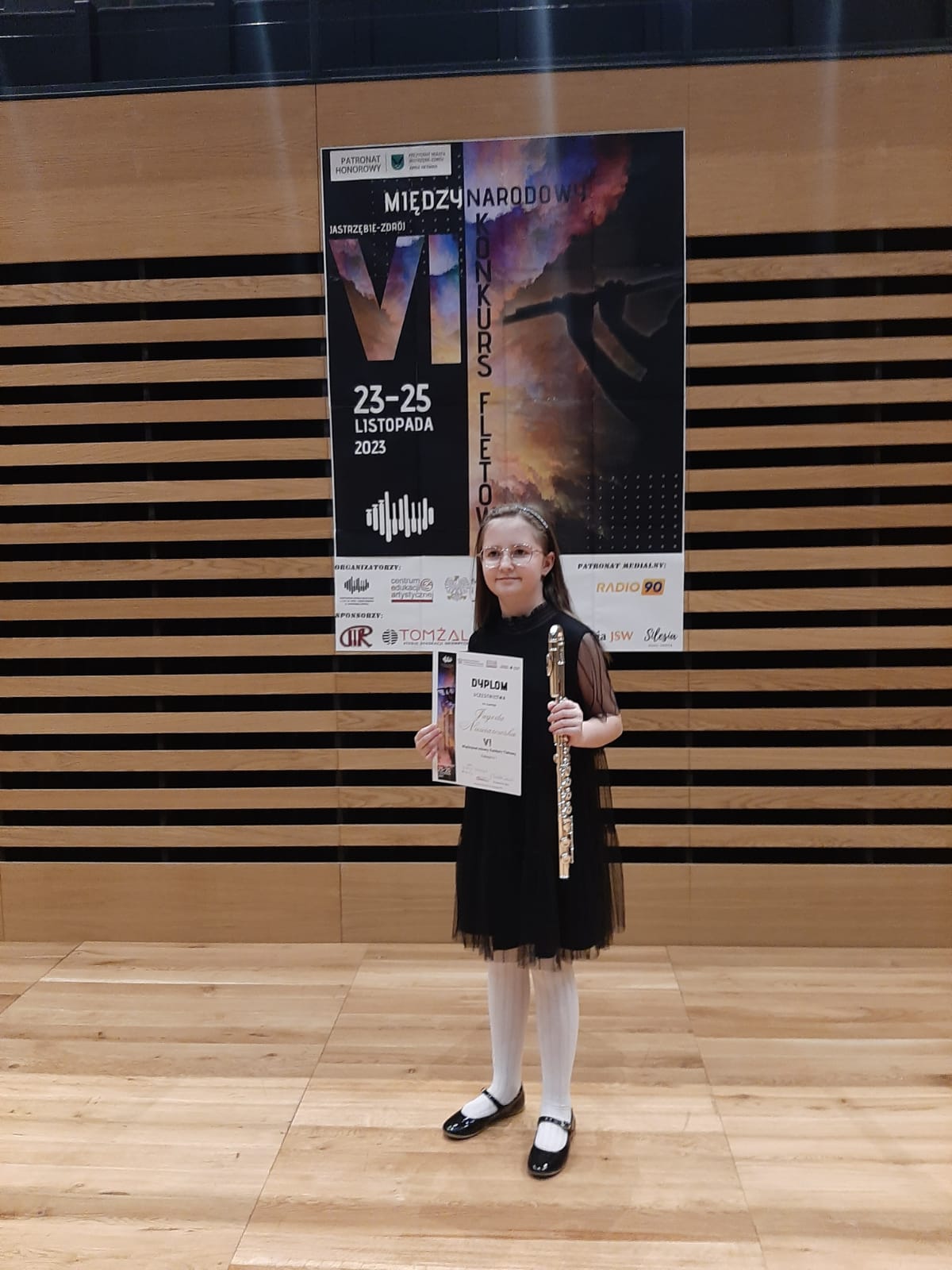 Uczennica z dyplomem na tle banera konkursu