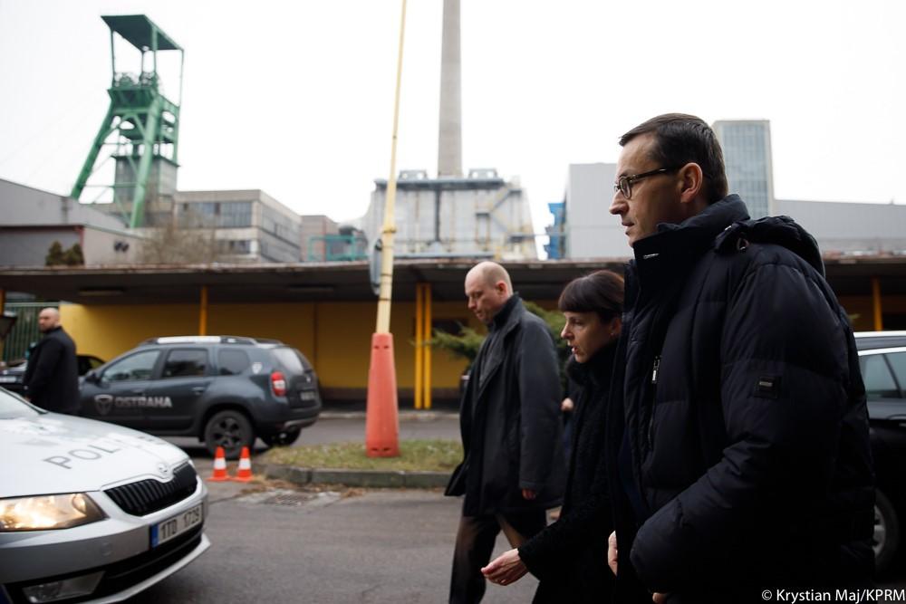 Premier Mateusz Morawiecki idzie, a w tle kopalnia.