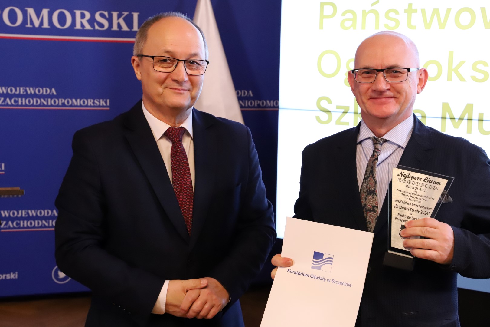 Zdjęcie przedstawia dyrektora ZPSM odbierającego od wicekuratora statuetki honorującej brązową szkołę