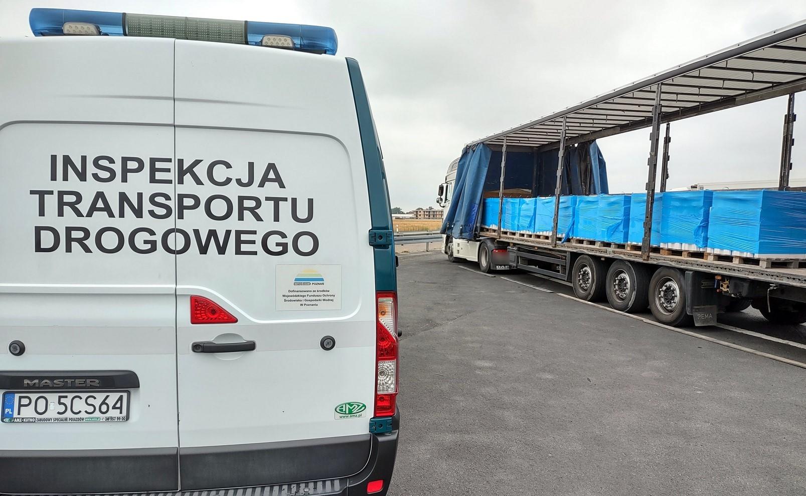 Widoczny tył radiowozu ITD i stojąca z prawej strony ciężarówka z odsuniętą plandeką na naczepie. 