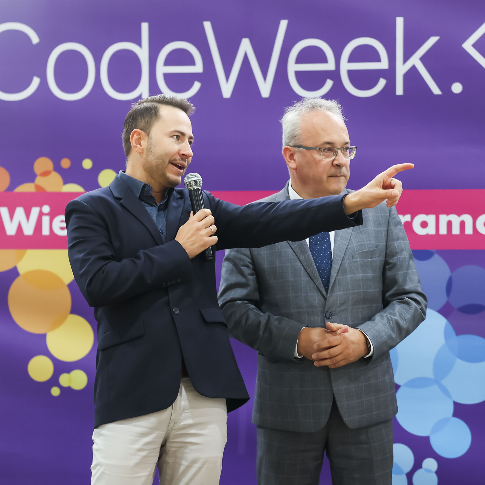 Przemawiający na tle ścianki Codeweek moderator wydarzenia, obok niego Burmistrz Augustowa Mirosław Karolczuk