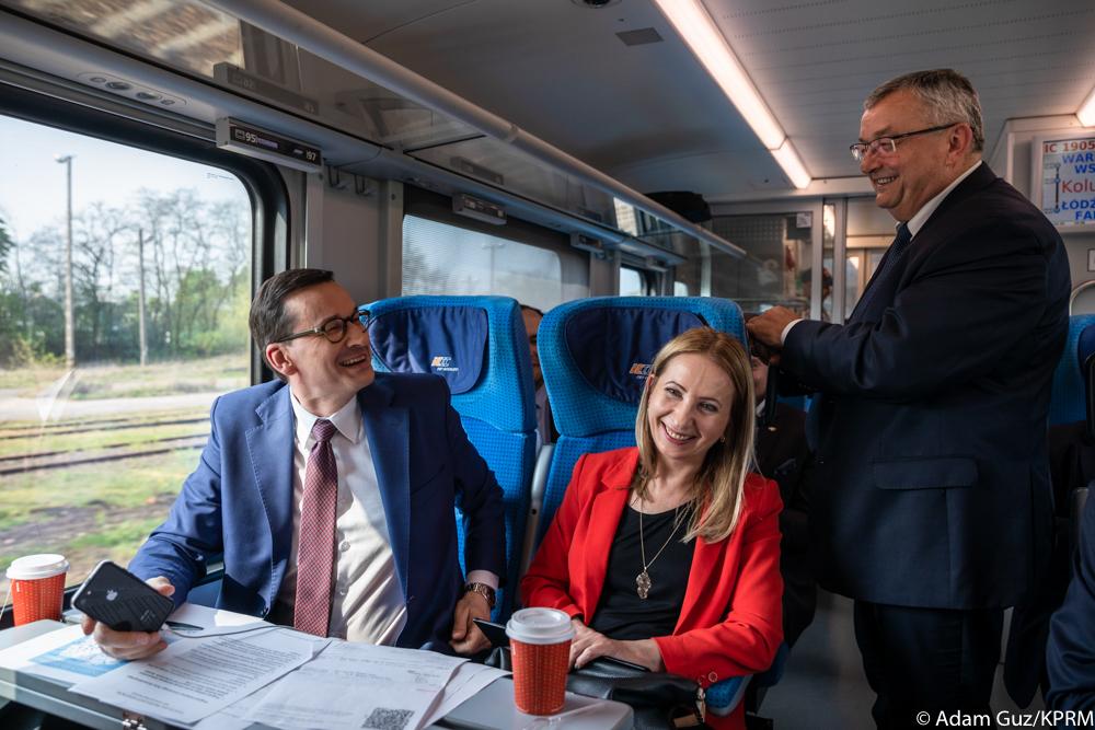 Od okna siedzi premier Matesz Morawiecki i rozmawia ze stojącym ministrem Andrzejem Adamczykiem.