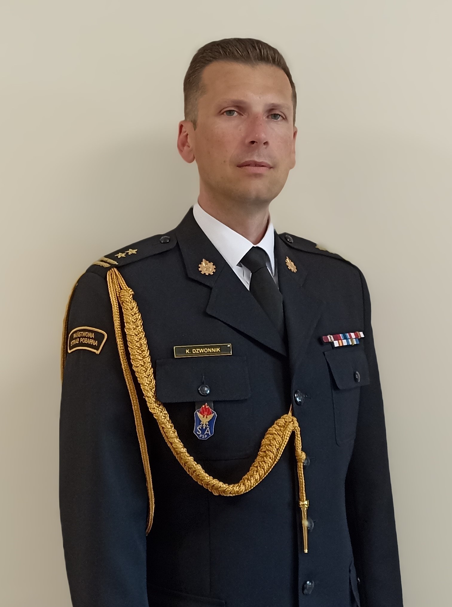 Zdjęcie brygadiera Kamila Dzwonnika w mundurze wyjściowym ze sznurem
