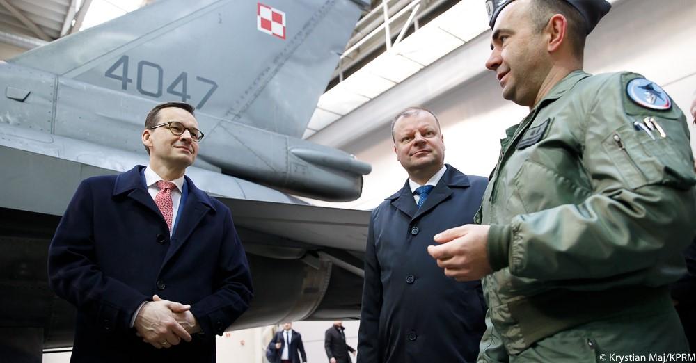 Premier Mateusz Morawiecki i premier Litwy rozmawiają z pilotem, a za nimi stoi samolot.