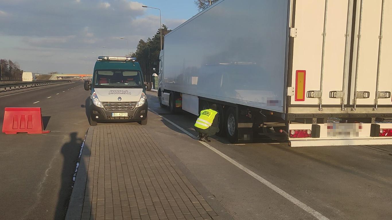 Inspektor kontroluje hamulce koła naczepy