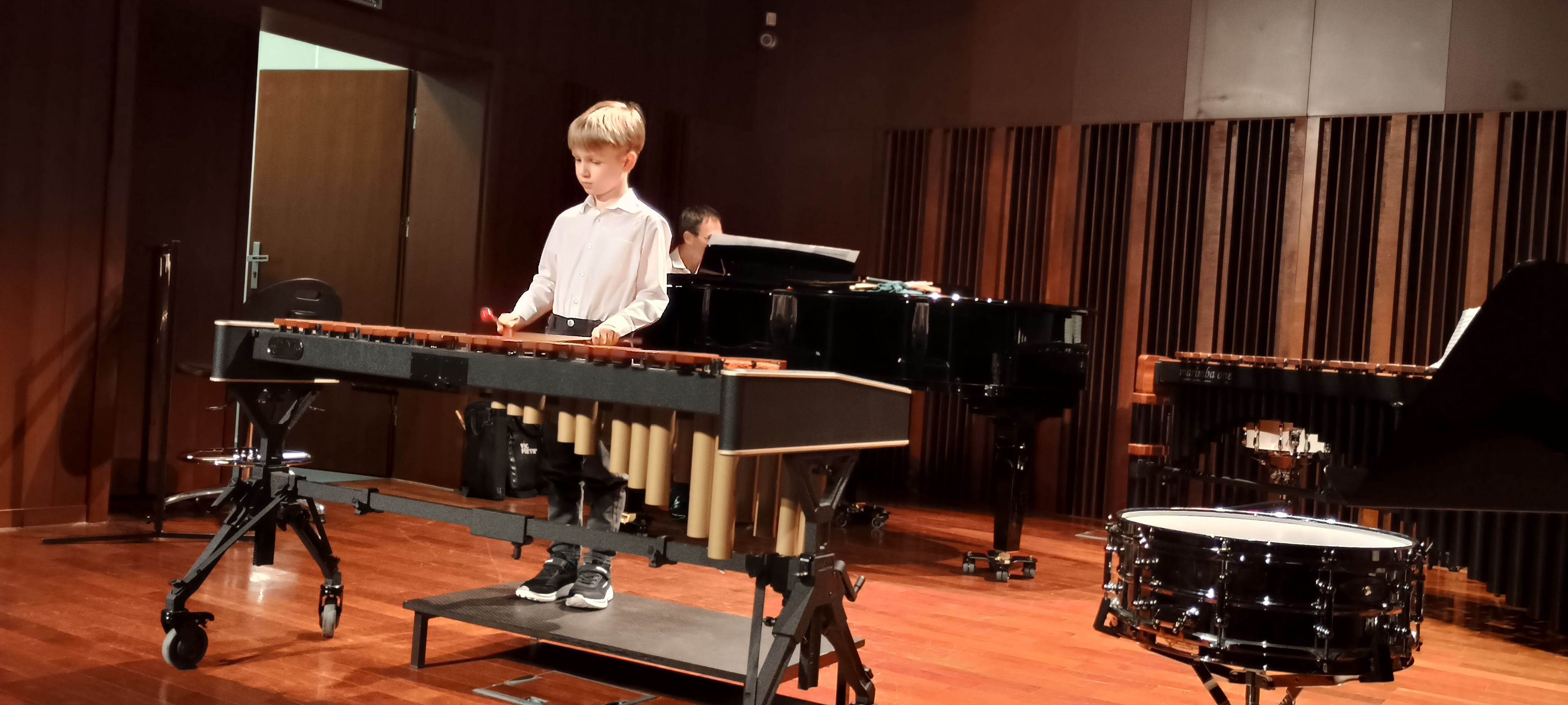 Warsztaty perkusyjne w szkole. Uczeń gra na marimbie na scenie sali koncertowej.