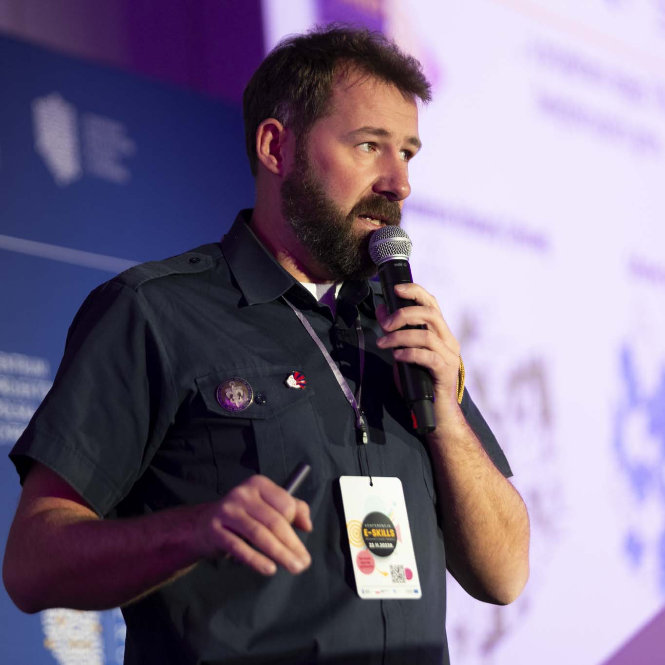 Pan Tomasz Rejmer, instruktor harcerski w stopniu harcmistrza trzyma mikrofon w ręku. Przemawia.