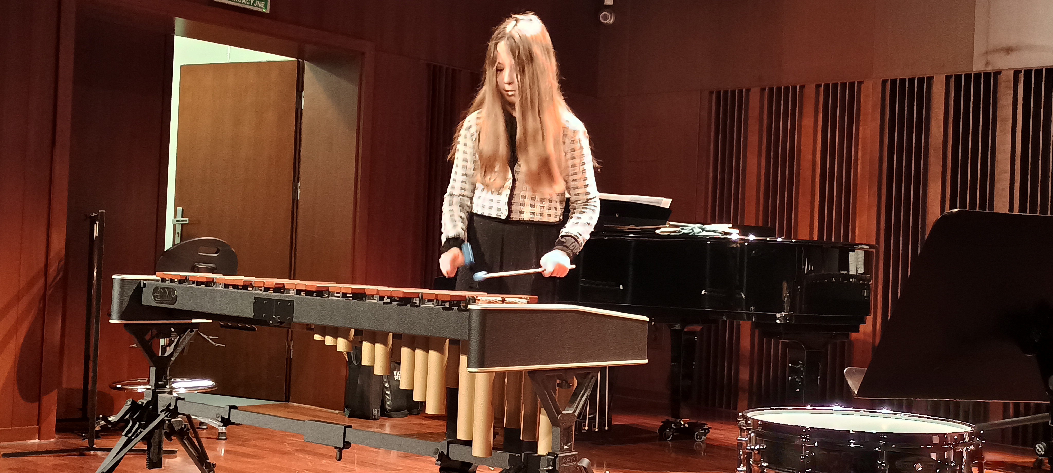 Warsztaty perkusyjne w szkole. Uczennica gra na marimbie na scenie sali koncertowej.