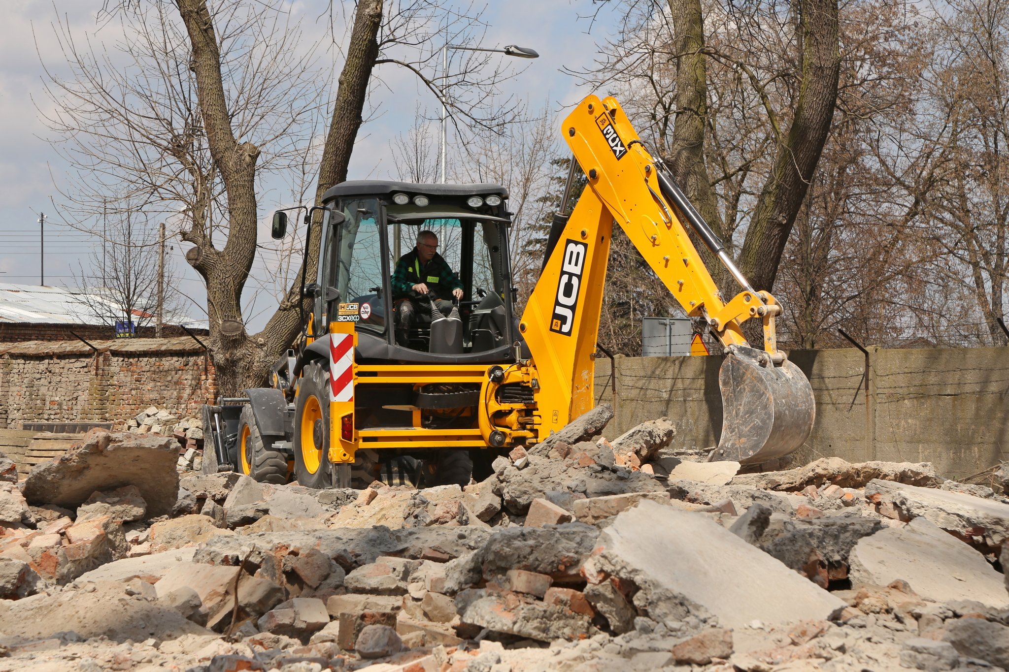Koparka w której siedzi operator pracująca na gruzowisku
