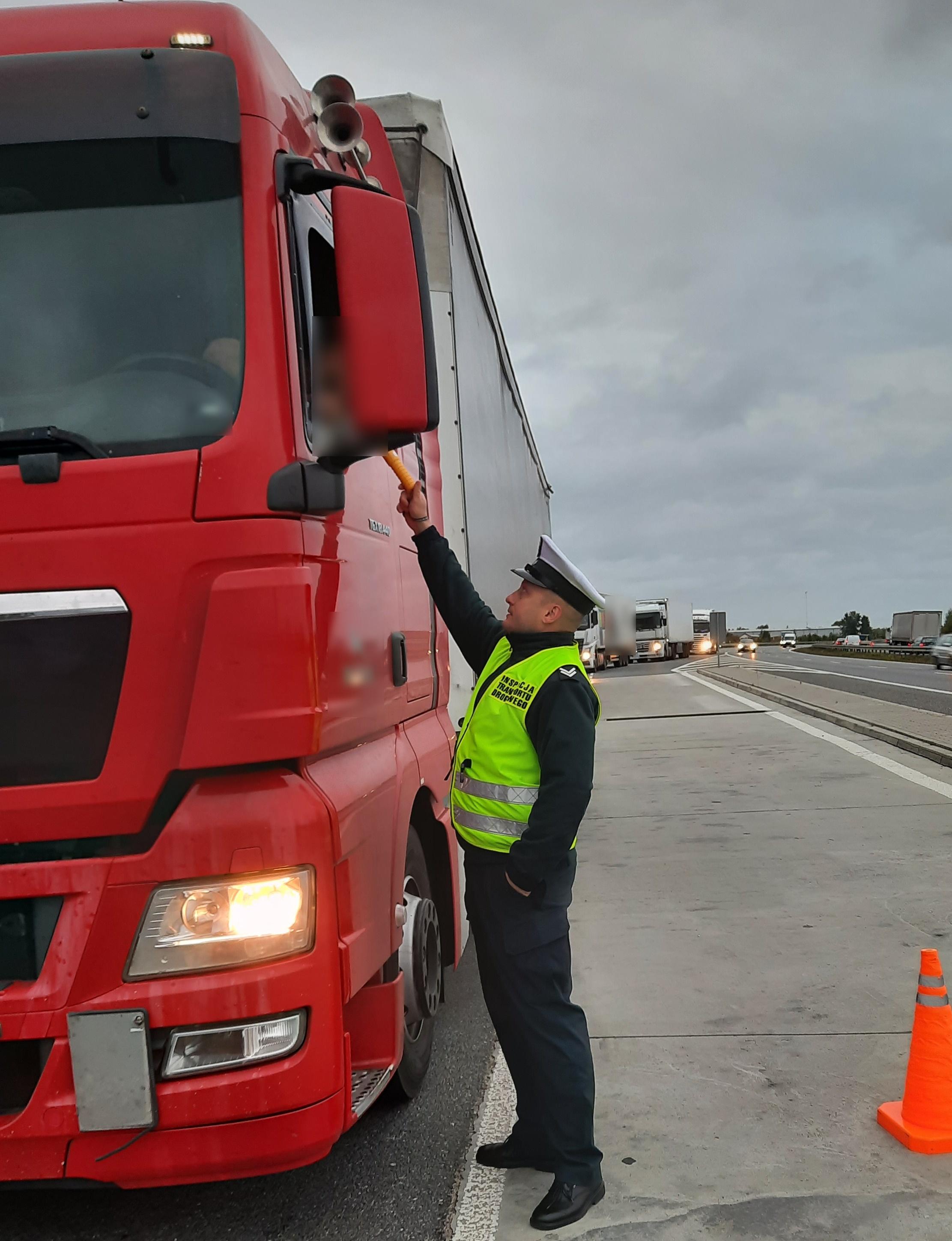 Inspektor bada trzeźwości kierowcy siedzącego w kabinie ciągnika siodłowego