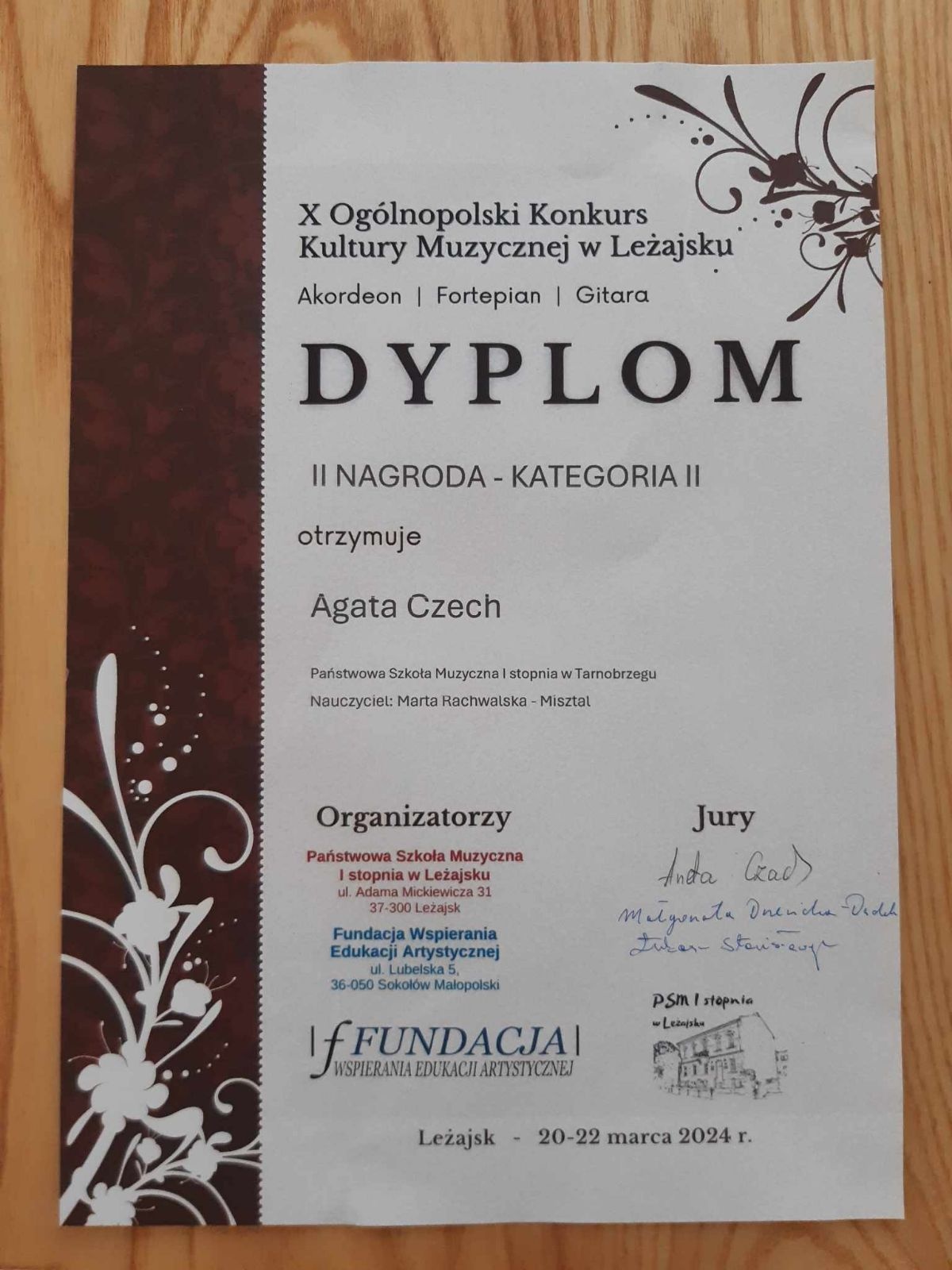 Dyplom zdobycia II nagrody w X Ogólnopolskim Konkursie Kultury Muzycznej w Leżajsku. W lewym dolnym rogu oraz w prawym górnym rogu ozdobne ilustracje. Na dole organizatorzy konkursu, a obok podpisy jury.