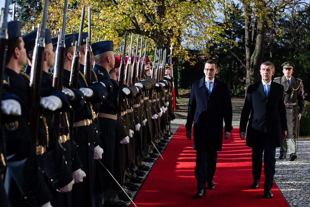 Premier Mateusz Morawiecki i premier Czech Andrej Babiš idą obok stojących w szeregu żołnierzy.