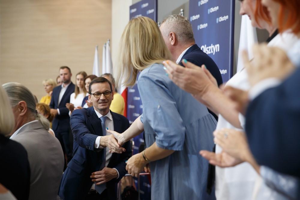 Premier Mateusz Morawiecki podaje dłoń uczestniczce spotkania.
