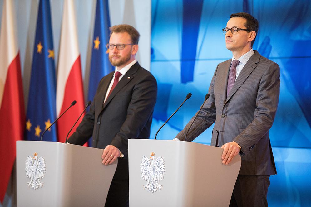 Premier Mateusz Morawiecki i minister Łukasz Szumowski przy mównicach podczas konferencji prasowej.