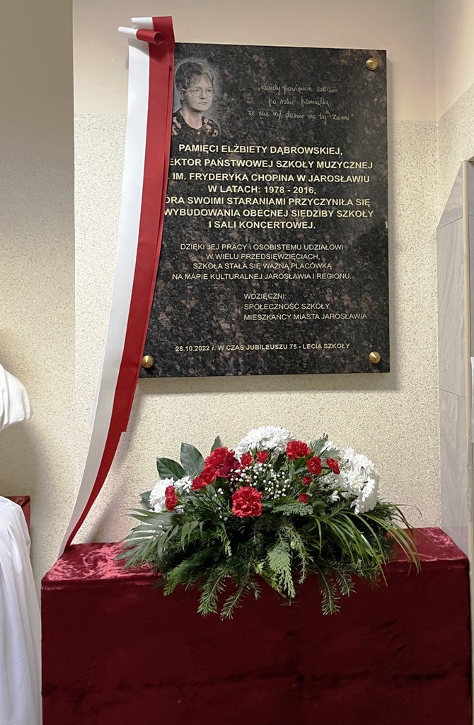 djęcie umieszczonej w hollu ZPSM w Jarosławiu pamiątkowej ciemnej, kamiennej tablicy poświęconej byłej dyrektor szkoły śp. Elżbiecie Dąbrowskiej. Oprócz wizerunku wieloletniej dyrektor PSM I st. im. F. Chopina w Jarosławiu znajduje się odwzorowany cytat, napisany przez nią odręcznie: „Każdy powinien zostawić pamiątkę, że nie żył darmo na tej ziemi”